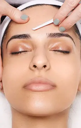A woman is receiving the dermaplaning treatment by an aesthetician