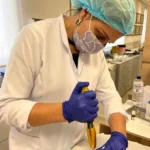 Esthetician with hair net, mask, gloves and lab coat applying the needleless mesotherapy procedure