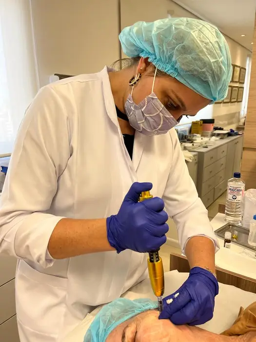 Esthetician with hair net, mask, gloves and lab coat applying the needleless mesotherapy procedure